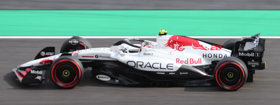 The white RB21 on track in profile, the green run-off band behind it, Honda on the rear bodywork and red markings running its length.